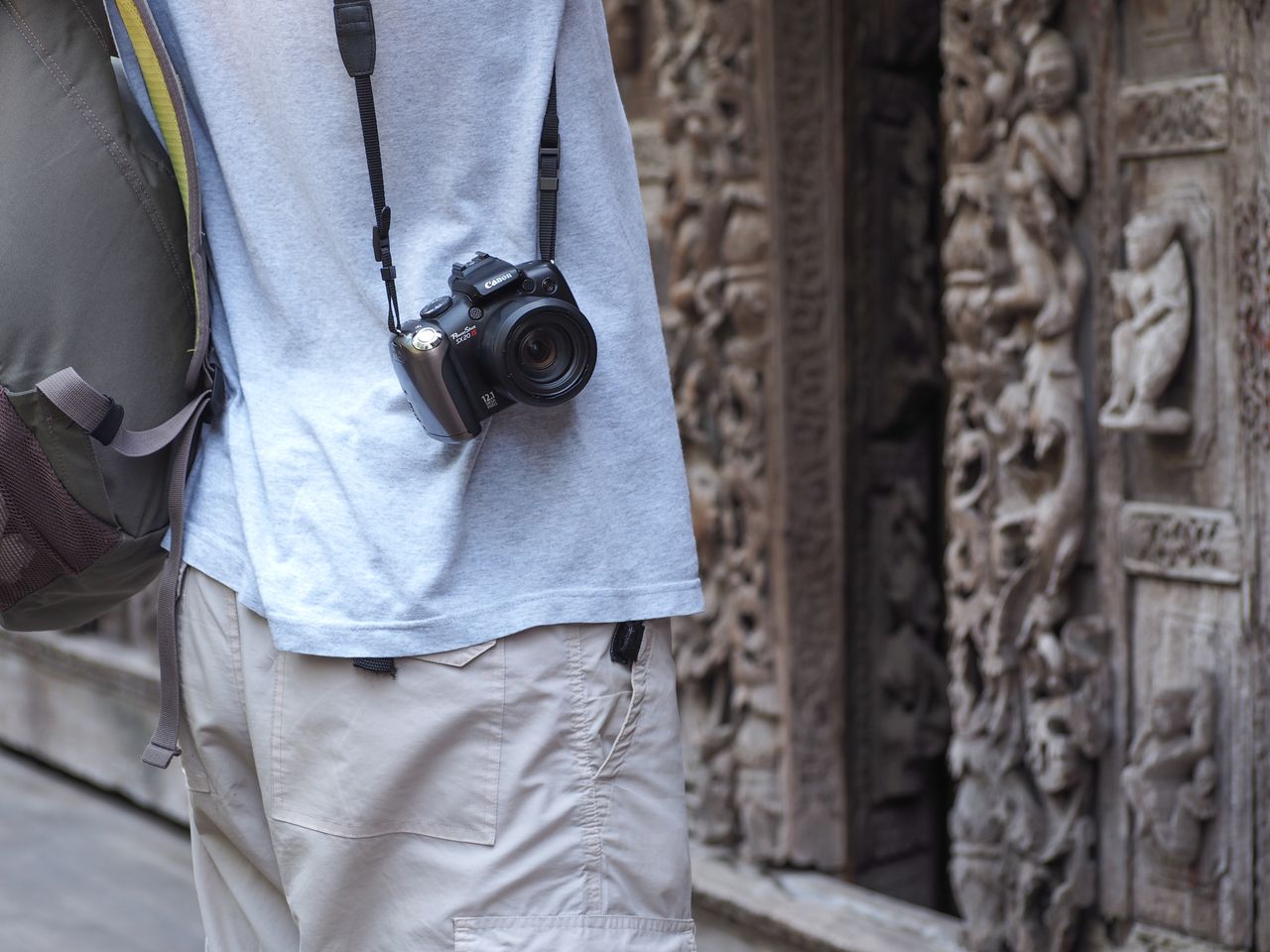 Back view of a traveler with camera exploring ornate historical site outdoors.