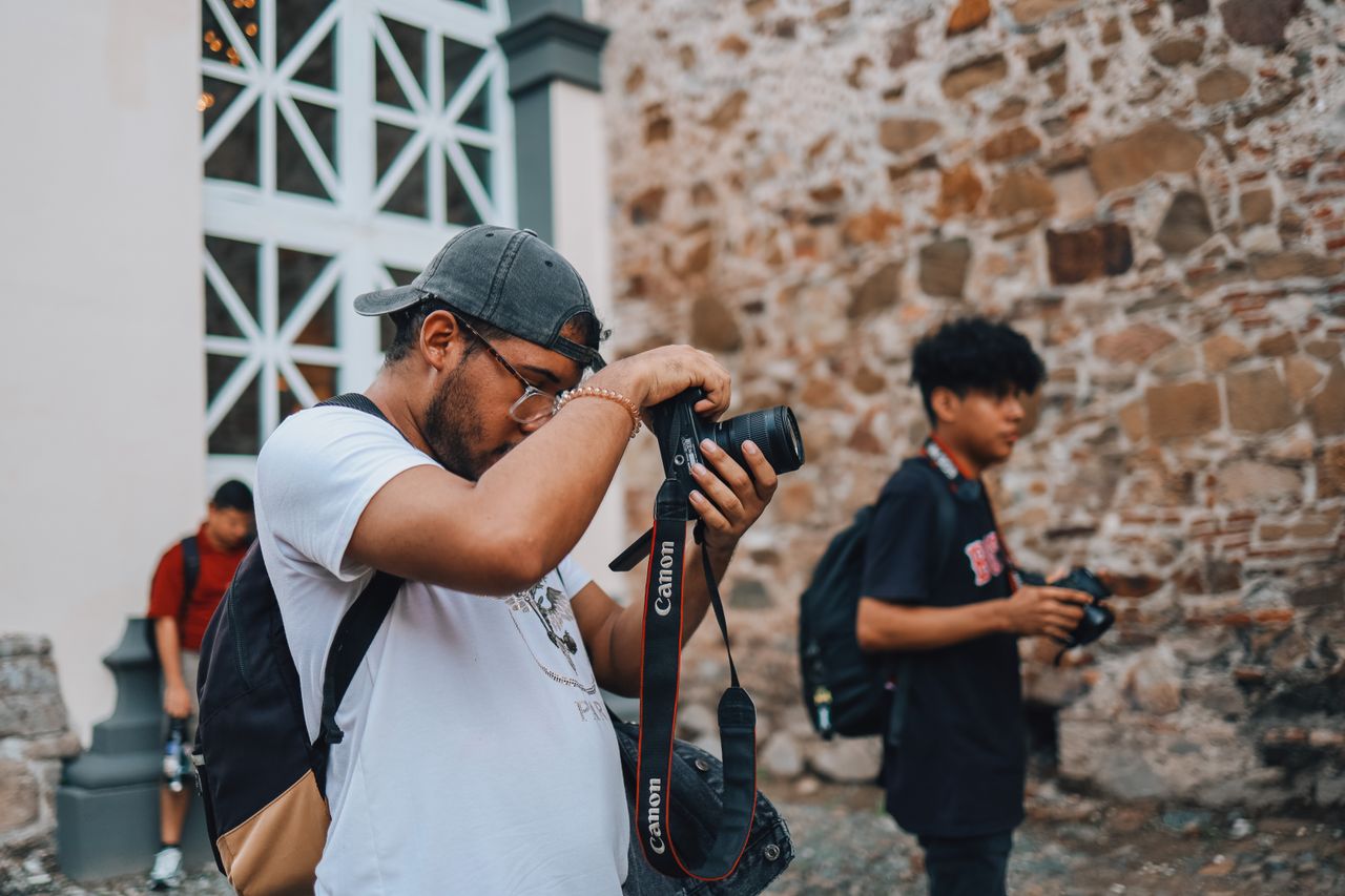 Two photographers capturing urban landscapes in a historic setting with stone walls.